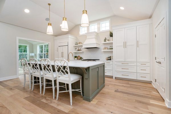 Covington Model view of the Gourmet Kitchen & Dining Room. Three gold pendants hang above an Olive Expanded Island with Quartz Countertops.