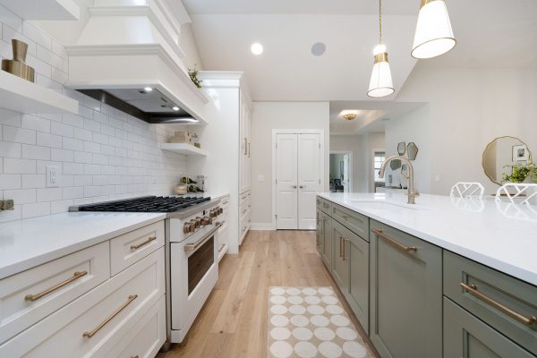 Covington Model view of the Gourmet Kitchen & Dining Room. Three gold pendants hang above an Olive Expanded Island with Quartz Countertops.